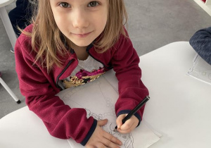 dziecko kalkuje obrazek na transparentnym papierze- przygotowanie do nauki pisania, rysowanie po linii